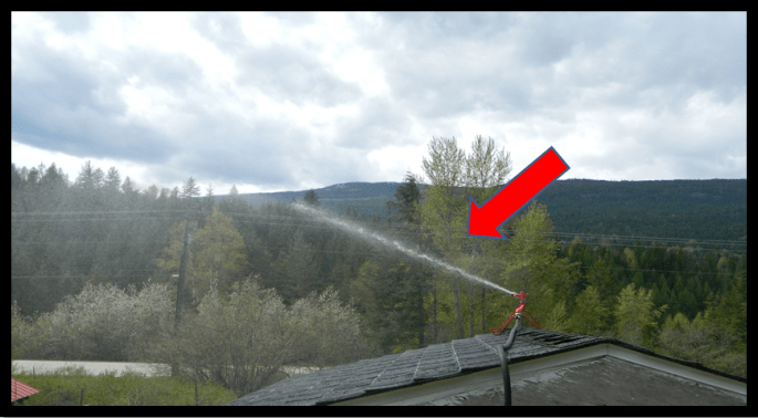 Photo Showing Trajectory Of Water Spray With A Firehawk Rooftop Sprinkler From The Roof Of A Shed In A Hobby Farm In A Wildland Urban Interface Area